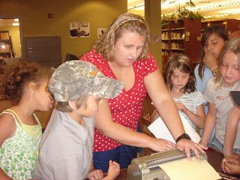 Showing kids how to use the brailler by writing their names
