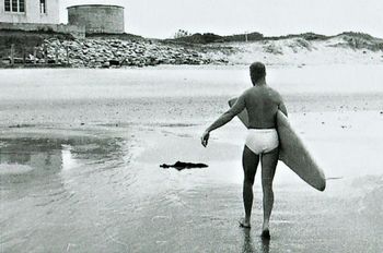 Terry Edge after a satisfying session at Waipu ..summer of '62 The old (surfclub) clubhouse up the top with the old watertank and sandbags to stop the erosion....
