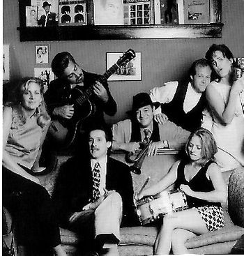 Vol II CD Photo (1996)~Mo, Eddie, Stephan, Bob, Chris, Jennie, Bec.  We took this photo in the home of friend, Patton James, and in the background, featured photos of family and musical influences.
