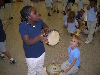 A girl speaks with a donno drum
