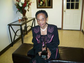 Mrs. Dora Bell holding the Rhythm Award presented to the Bell Singers
