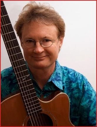 Greg Tamblyn smiling with guitar
