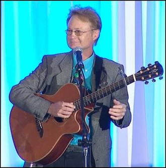 Greg Tamblyn onstage with guitar, looking at audience