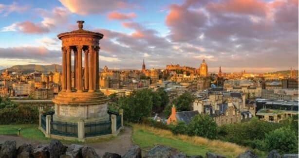 View of Edinburgh from a hill with a monument, and Edinburgh Castle in the distance