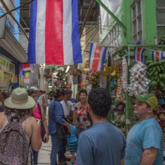 People walking in a market with a flag of Costa Rica hanging from the ceiling