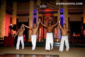 Four handsome Capoeira in top form with shirts off, hands joined and raised proudly after a samba floor show party performance
