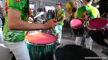 Three samba drummers in bright green & blue shirts playing drums at a birthday party. You choose your party performers
