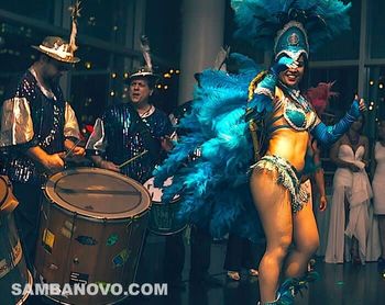 Two samba drummers and one samba dancer in blue and silver costumes performing a live custom samba show at a corporate event
