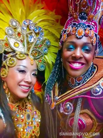 A closeup of two Brazilian samba dancers for hire in beautiful makeup, and wearing shining, colorful, sequined costumes
