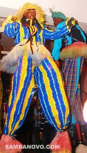 Looking up at one giant moco jumbie in a blue and yellow costume while he is entertaining at a party
