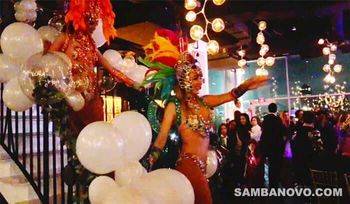 Two samba dancers coming down stairs entering a large birthday party full of event entertainment
