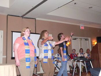 Justin, Marsha Stevens, and Sandi Baker leading the conference choir at a rehearsal
