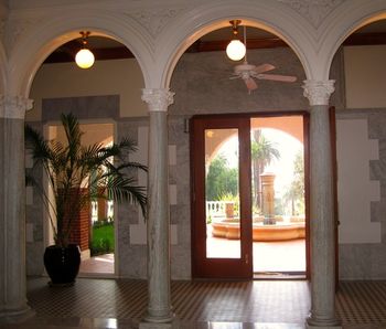 The mansion's interior spaces are impressive, with vaulted ceilings, marble pillars, contiguous arches, and potted palms.
