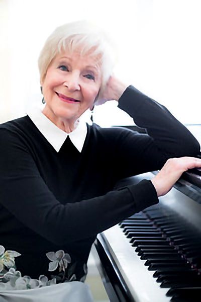 Photograph of Toby Blumenthal posing by a Steinway Piano