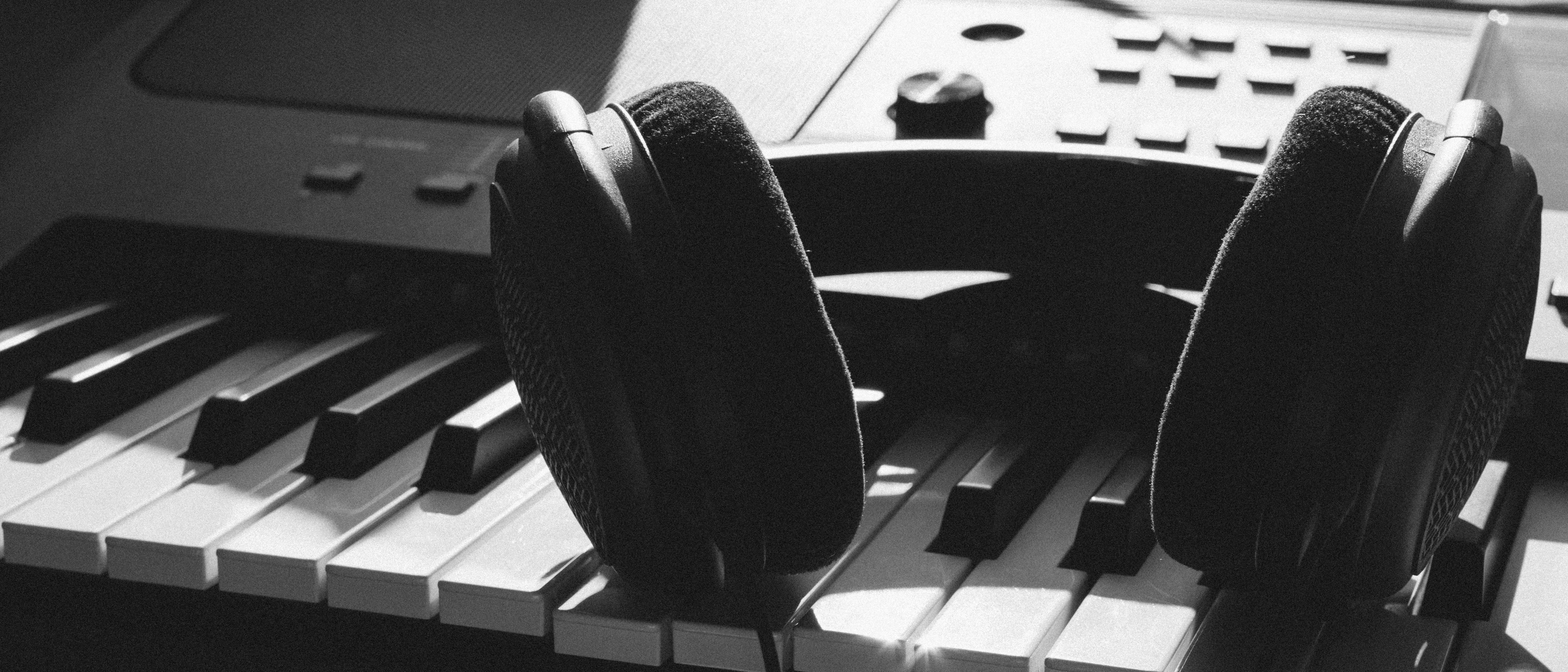 Black wireless headphones resting on a sleek gray electronic keyboard