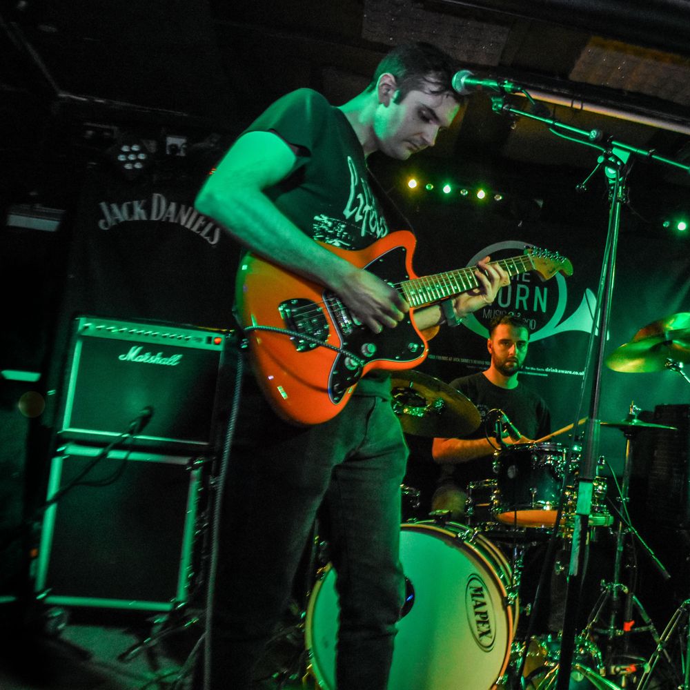 guitarist and singer frontman performing live at a gig in the United Kingdom