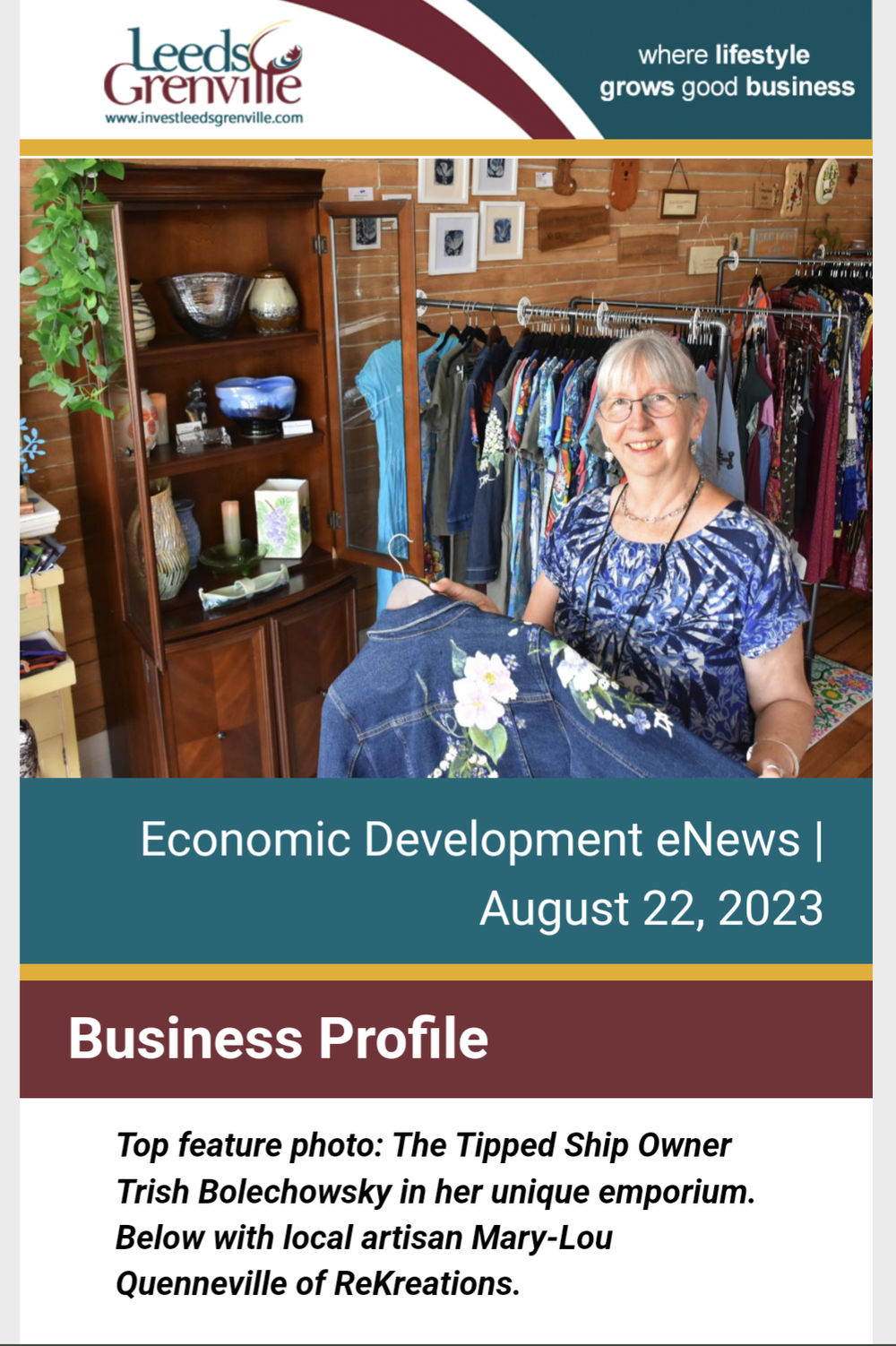 Image of owner of The Tipped Ship, Trish Bolechowsky, holding a painted jean jacket in front of clothing racks in her shop 