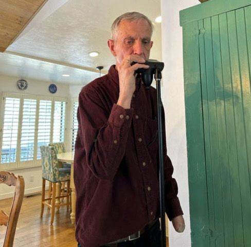  John Kally demonstrates the customized device that will aid him in continuing  to play the harmonica despite the amputation of his left hand.