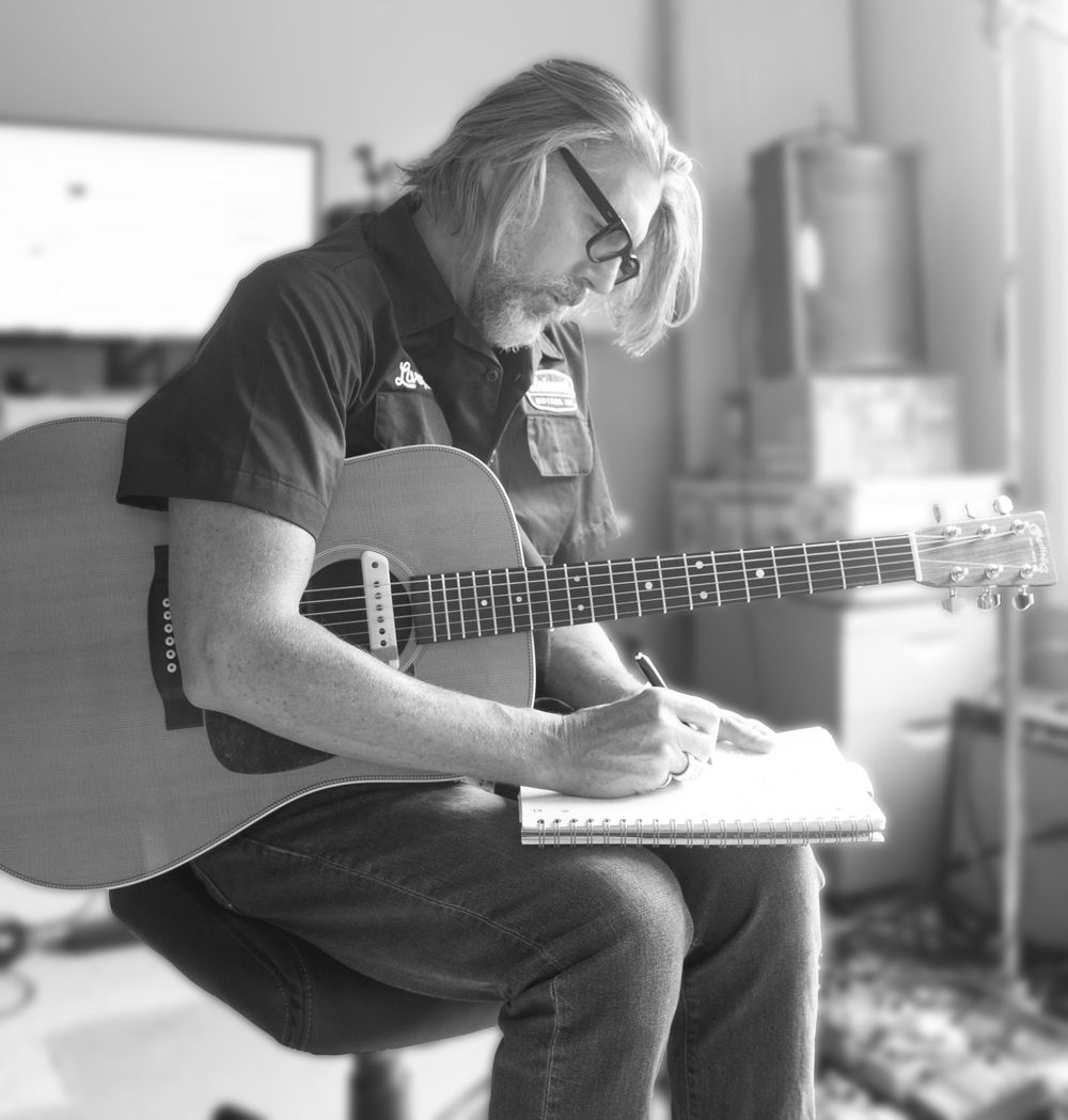 Scott Hall Musician and Songwriter writing lyrics on a notepad while holding