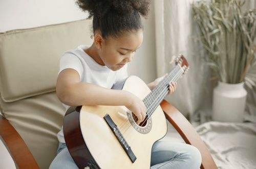 young girl smiling while practicing guitar