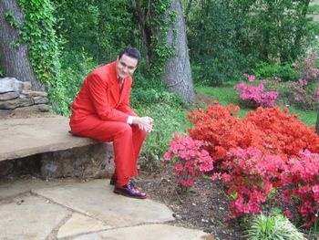 It takes a man to sit in a red suit by azaleas.
