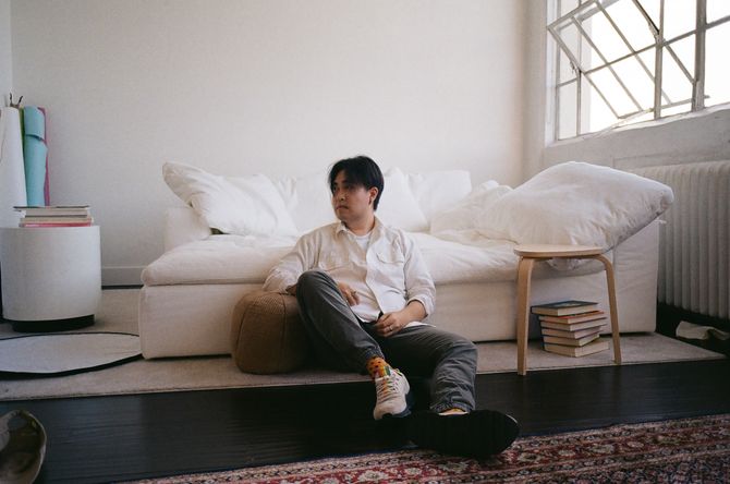 Man leaning against white couch in sunlight loft