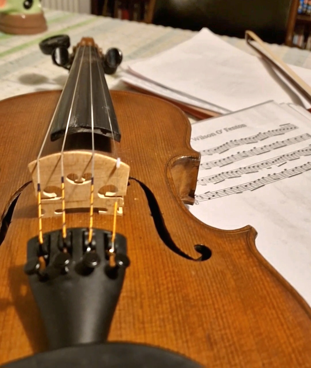 A violin on a table next to some sheet music