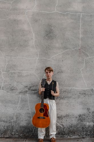 Katherine Paterson posing with guitar in one hand and a flower in the other