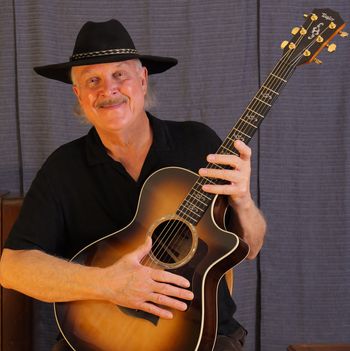 New photo, Nov 2023. With my Taylor guitar and my old black hat!
