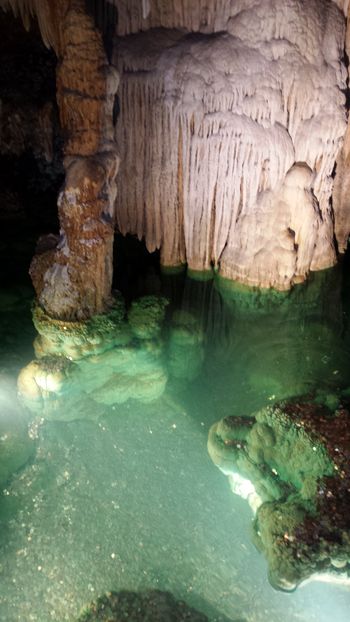 stalactites and stalagmites form a column in this mirrored pool.
