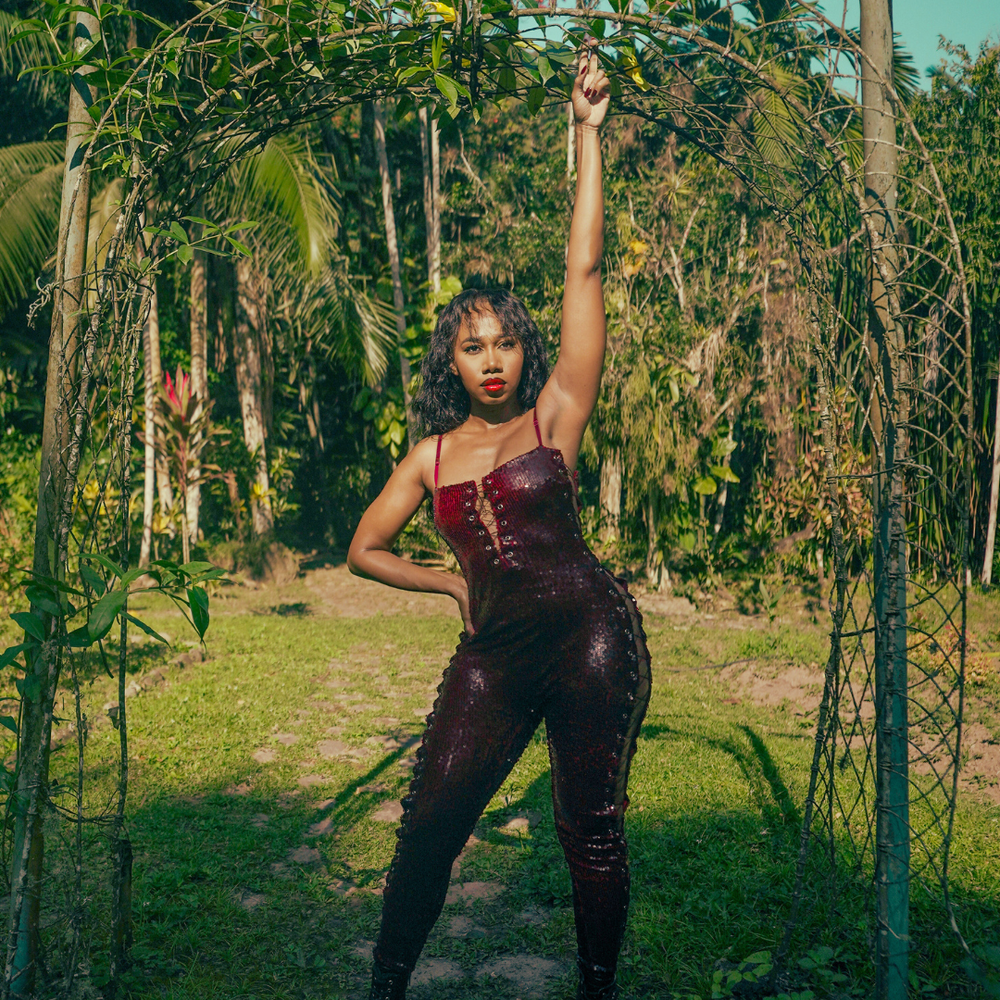 Black Female in a burgundy sequined jumpsuit in a garden in Jamaica