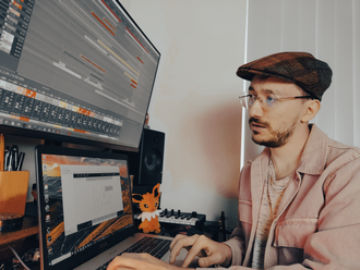 Cataldo Cappiello working on one of his tracks, sitting in front of two screens displaying a digital audio workstation.