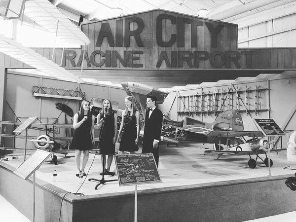 Black and white photo of Vintage Mix singing at an airport.