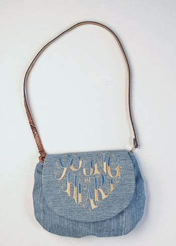 Young at Heart embroidered on upcycled denim. The strap is a belt.
