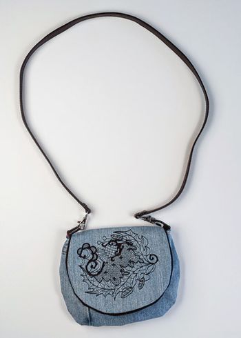 Blackthorn circle embroidered on upcycled denim. The strap is a belt.
