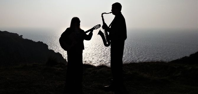guitar and saxophone duo posing in silhouette