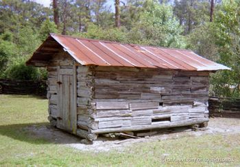 This looks like a corncrib, however it has been modified and the open spaces between slats have been filled. Corncribs  must have spacing in between slats to allow the air to dry the corn.
