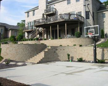 1st phase - upper wall and patio under deck 2 nd phase lower patio and fire pit and stair case to basket ball court note: to my left is a play ground area supported by another retaining wall Elevation changes are our specialty
