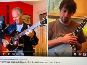 A photo of Brooks Williams with an acoustic guitar and Dan Walsh with a banjo