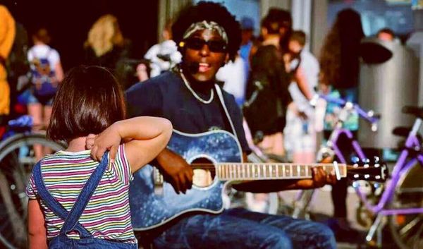 Ryan Koriya busking at Alexanderplatz in Berlin with a young girl in awe - Photo by Wolfgang Stegherr