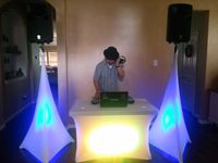Wedding reception setup with lighted speaker stand scrim and table cover. 