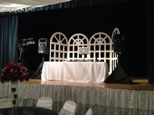 white DJ table on stage with wrapped speaker stands