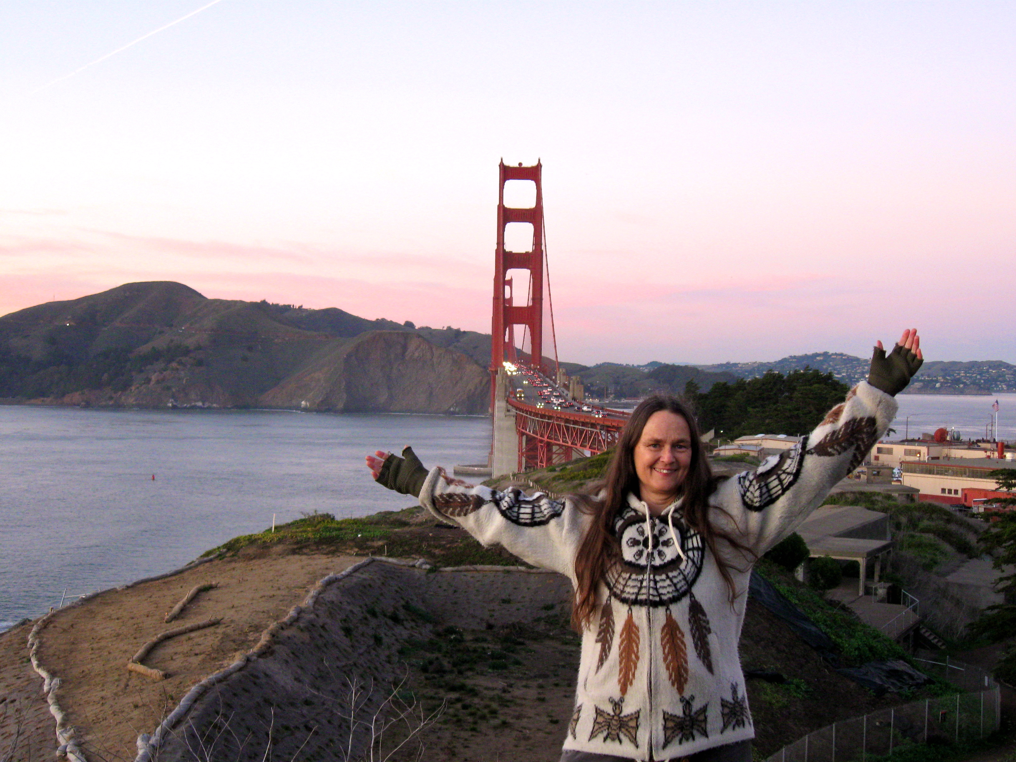 White woman with arms extended, Golden Gaet Bridge tower in background 