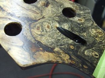 After some artistic cosmetic repair, you can no longer see the cavity in the headstock veneer.
