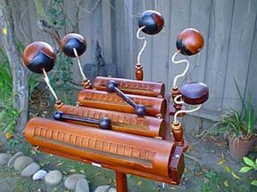 This is a classic Vietnamese percussion instrument known as a Danmo.  Its hand carved from the highly resonant Jack Fruit tree and consists of a wooden stand, five tuned temple blocks and four tone blocks with scrapers (maker unknown).  The unique sound is produced with two double-ended mallets. (kind of looks like a Dr. Seuss thing-um-a-jig )