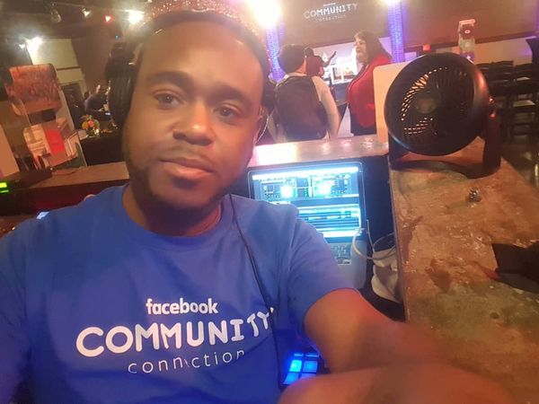 DJ Tron taking a selfe while DJing with a Facebook tee shirt on