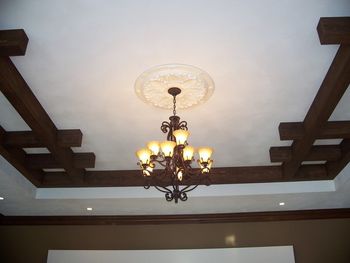 Rustic finished beams with a painted mediallon for the chandelier.
