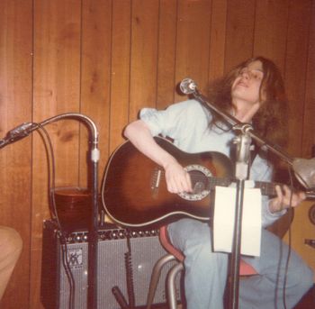 A long-haired, teenage Dave playsan Ovation guitar at a college coffeehouse.
