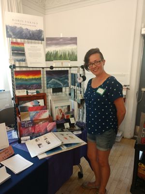 Robin Yukiko stands next to their art display at the Bi Arts Festival.