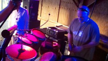 Bezl prepares his custom djembe drum kit during sound check at Srirus Rising while Billy Woods looks on

